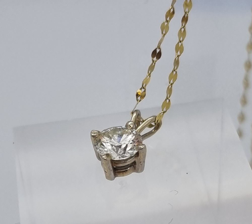 A round brilliant cut diamond set in a four-claw yellow gold pendant mount on a fine chain. View XVIII