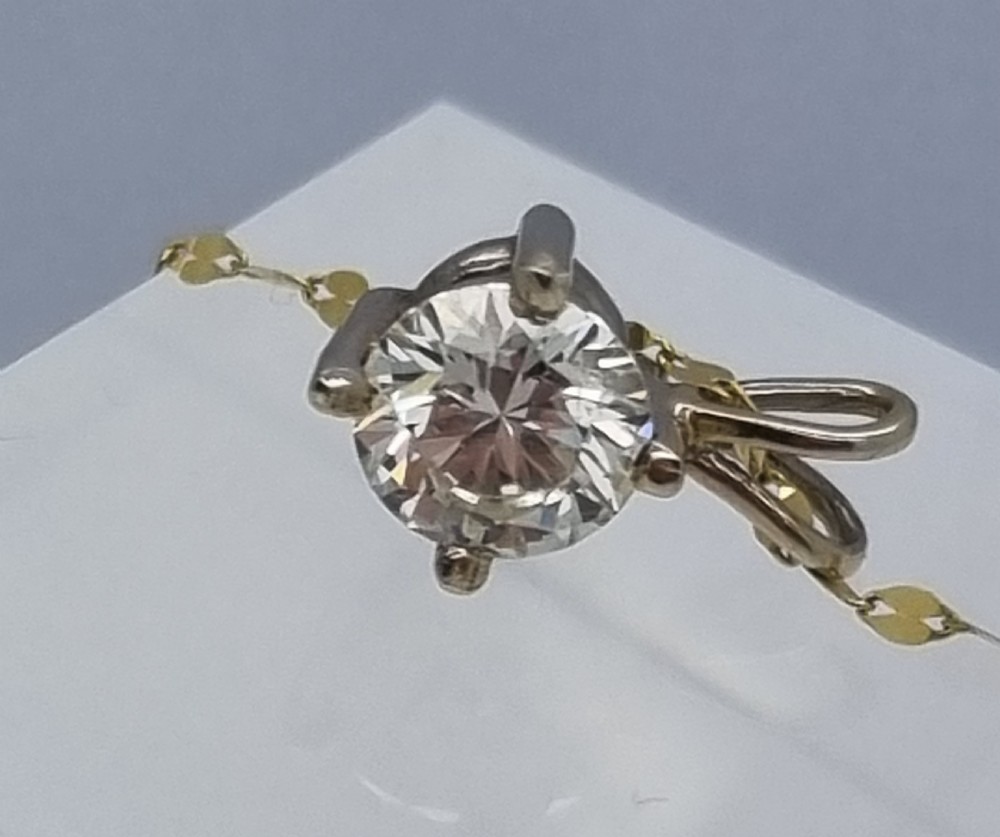 A round brilliant cut diamond set in a four-claw yellow gold pendant mount on a fine chain. View XIX