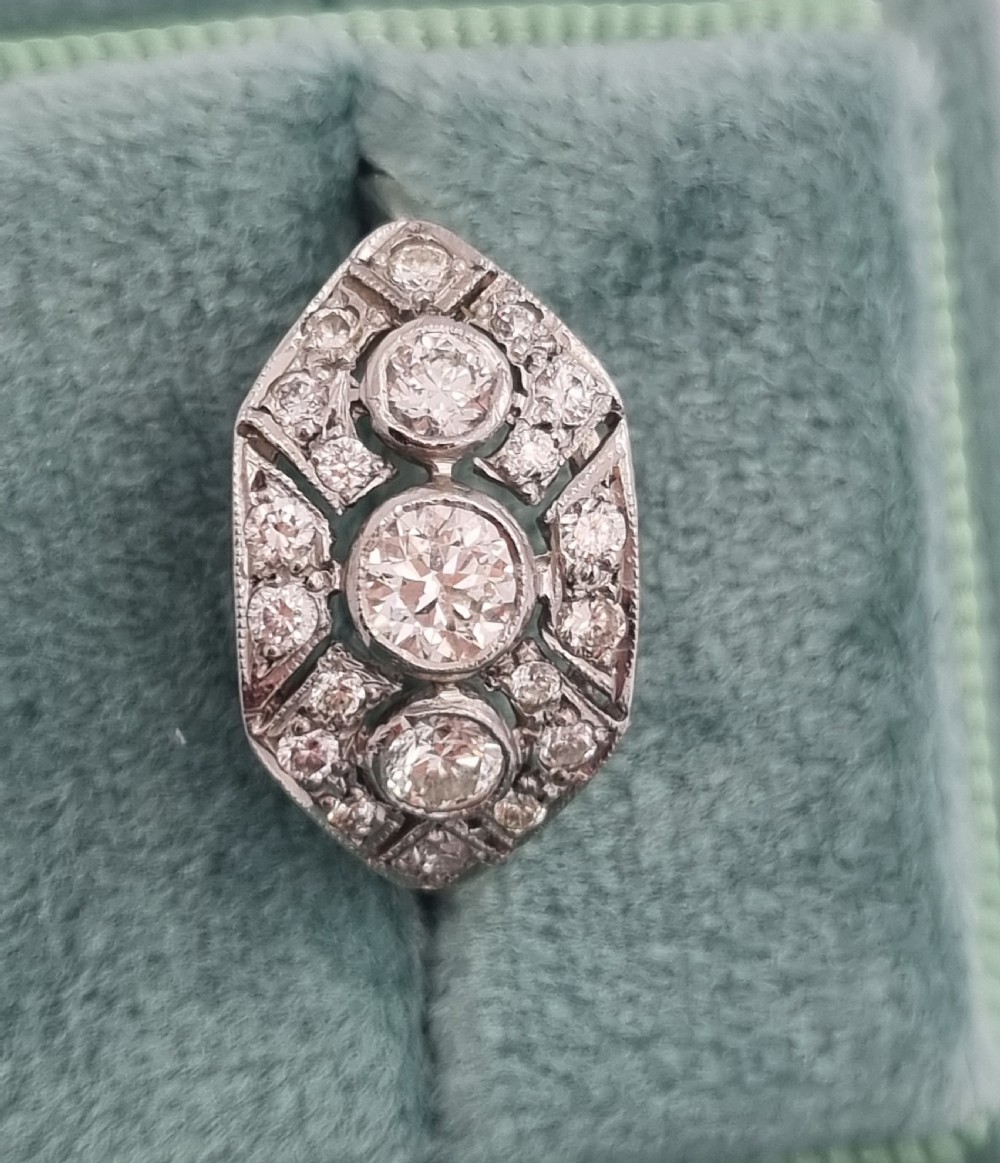 An Art Deco platinum ring head featuring a geometric marquise motif set with three central round diamonds in rubover settings surrounded by smaller pave-set diamonds.