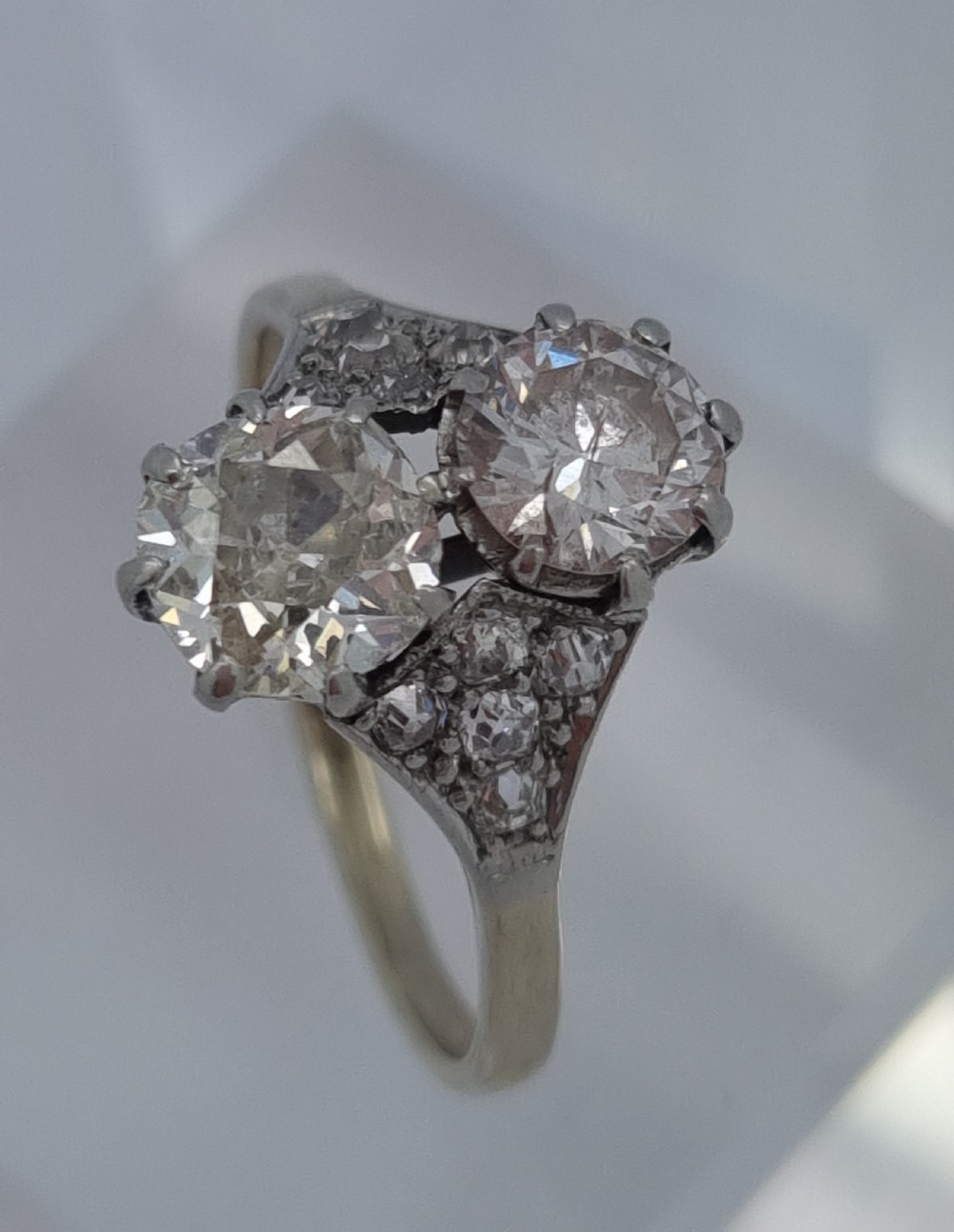 An Art Deco period two-stone diamond ring featuring vertically set principal stones flanked by pave-set diamond shoulders. View XI