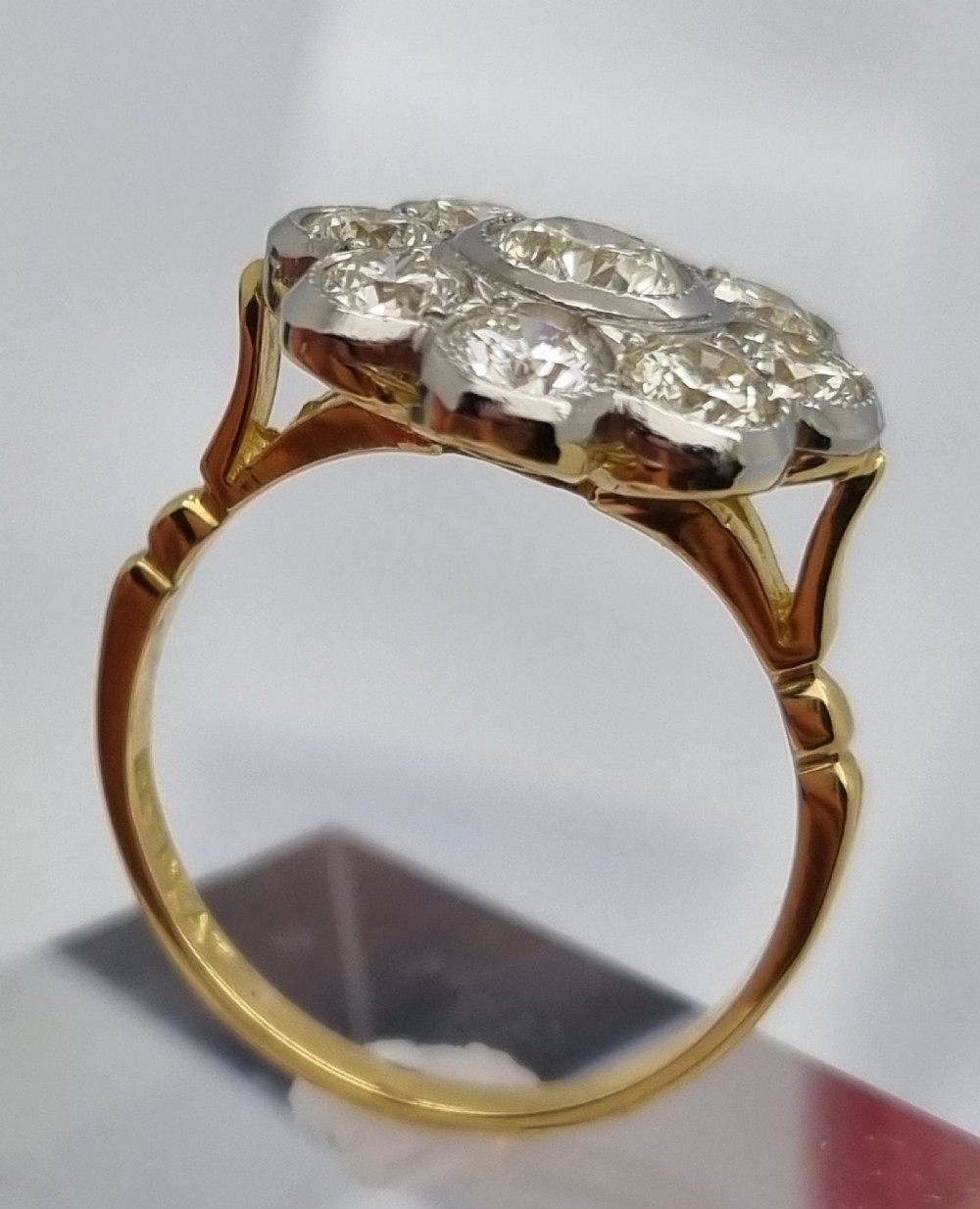 An 18ct yellow gold ring featuring a platinum-set floral head diamond cluster with a central round diamond encircled by eight surrounding diamonds. View II