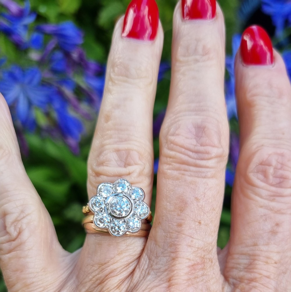 An 18ct yellow gold ring featuring a platinum-set floral head diamond cluster with a central round diamond encircled by eight surrounding diamonds. View III