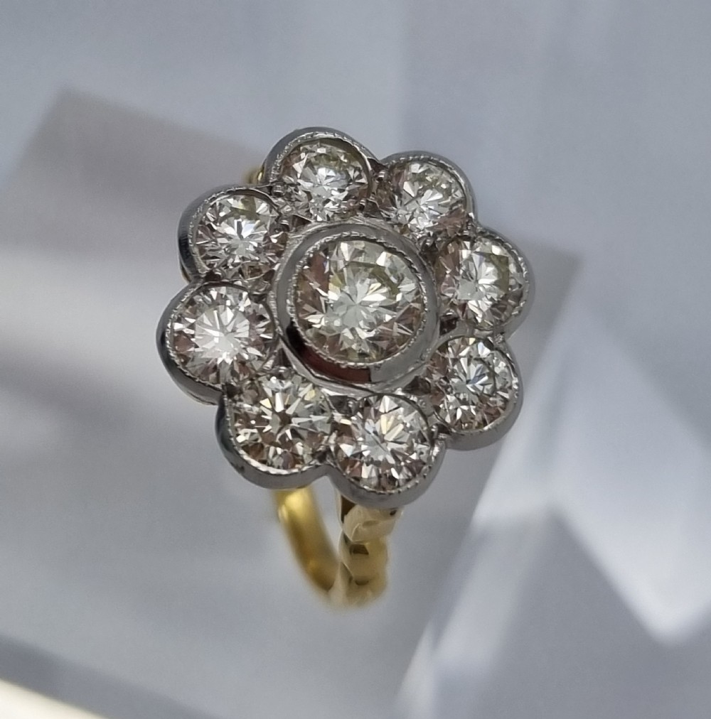 An 18ct yellow gold ring featuring a platinum-set floral head diamond cluster with a central round diamond encircled by eight surrounding diamonds. View VII