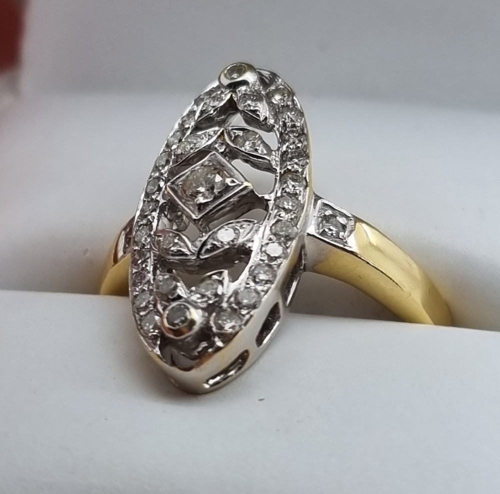 An antique yellow gold ring featuring an elongated oval pierced panel set with small diamonds and a central diamond motif. View VI