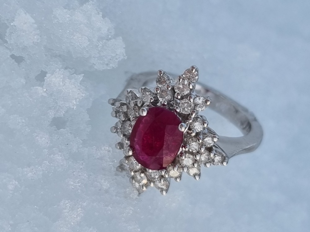 An 18ct white gold cluster ring featuring a central cushion cut ruby surrounded by a starburst halo of diamonds. View IV