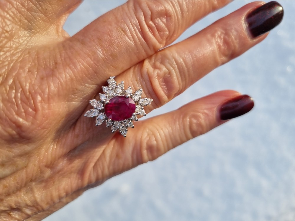 An 18ct white gold cluster ring featuring a central cushion cut ruby surrounded by a starburst halo of diamonds. View XII