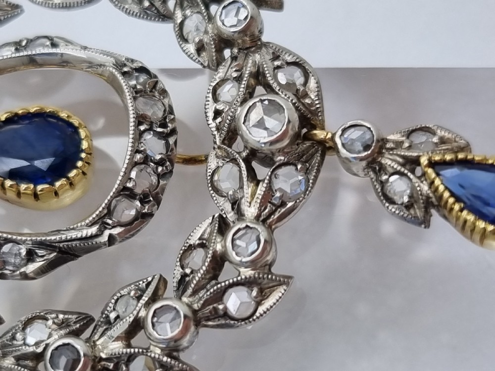 An Edwardian bow and garland design brooch pendant crafted in silver-topped gold, set with diamonds and teardrop blue sapphires. View III