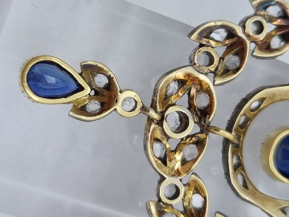 An Edwardian bow and garland design brooch pendant crafted in silver-topped gold, set with diamonds and teardrop blue sapphires. View VII