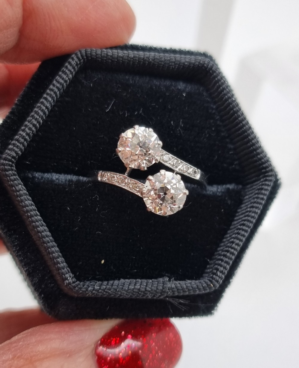 An Art Deco platinum twist ring featuring two central round diamonds in a crossover setting with diamond-set shoulders. View II