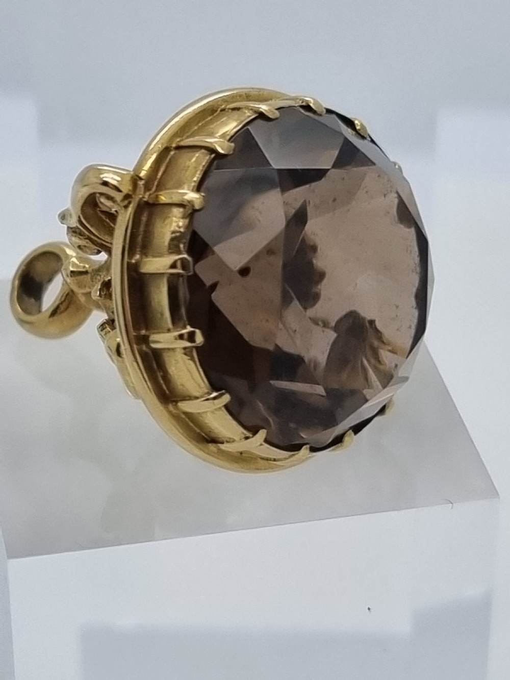 An ornate 9ct gold watch fob pendant set with a large faceted smokey quartz gemstone and detailed scrollwork frame. View VI
