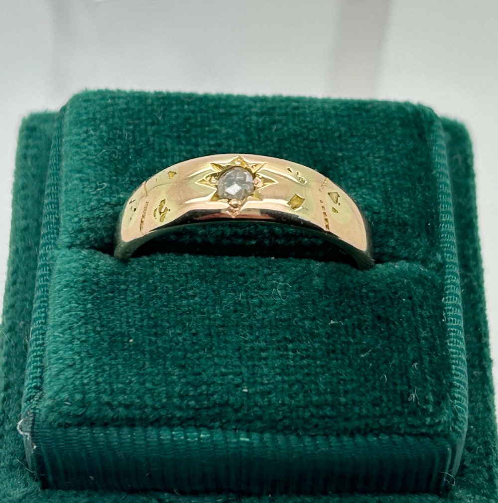 A yellow gold band ring featuring a single clear gemstone embedded within a carved starburst celestial motif. View II