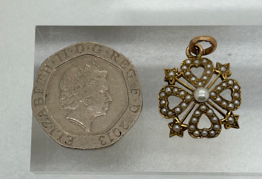 An antique Victorian openwork gold pendant set with seed pearls featuring a four-lobed heart motif with star points. View VIII