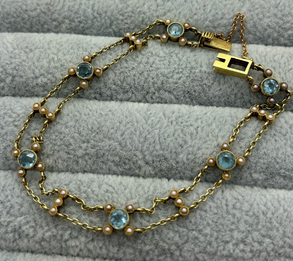 A late Victorian 15ct gold double trace chain bracelet set with round faceted aquamarines and split seed pearls.