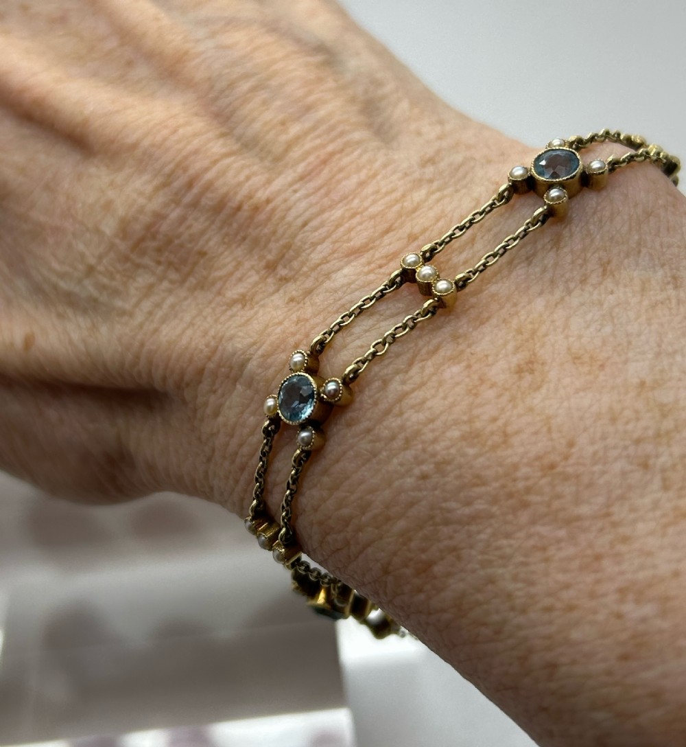 A late Victorian 15ct gold double trace chain bracelet set with round faceted aquamarines and split seed pearls. View II