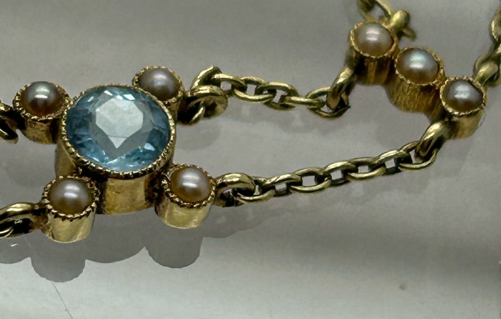 A late Victorian 15ct gold double trace chain bracelet set with round faceted aquamarines and split seed pearls. View IV