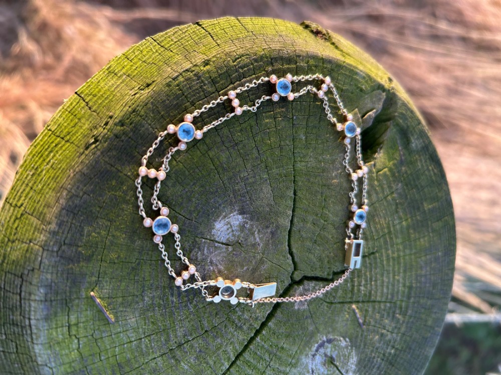 A late Victorian 15ct gold double trace chain bracelet set with round faceted aquamarines and split seed pearls. View XVI