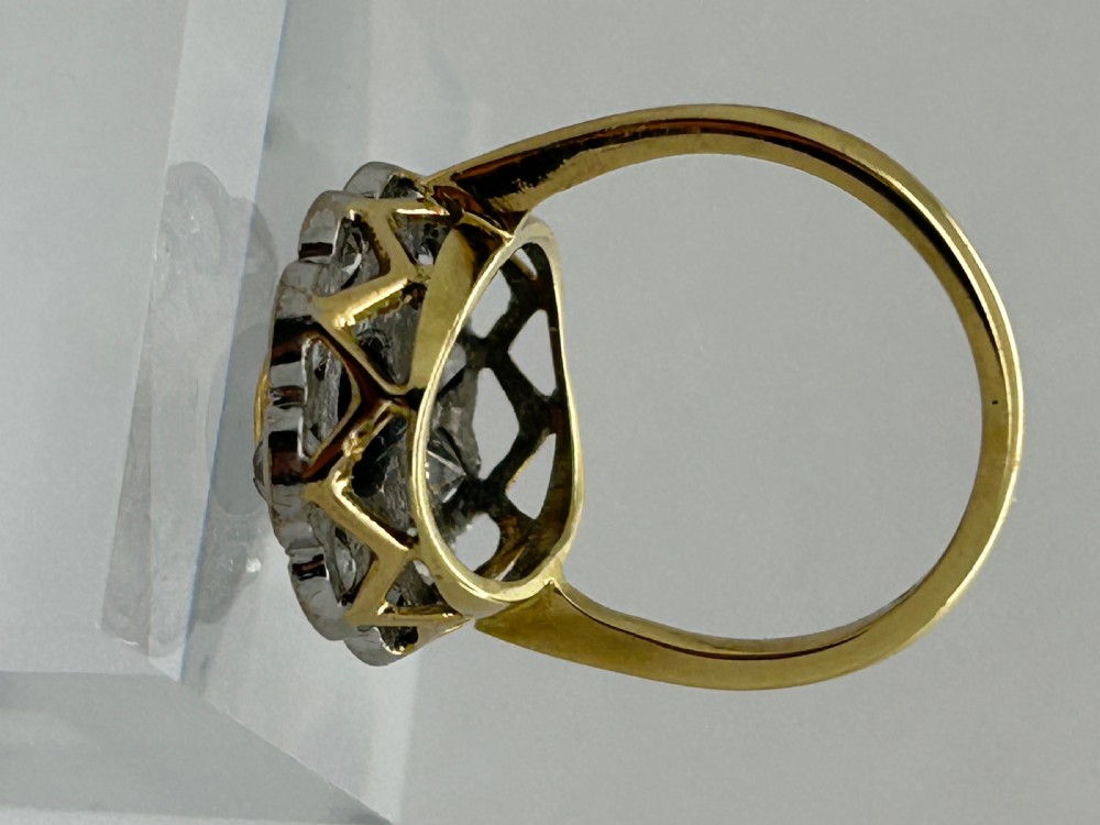 A yellow gold cluster ring featuring a central oval dark blue sapphire framed by a scalloped halo of round cut diamonds. View III
