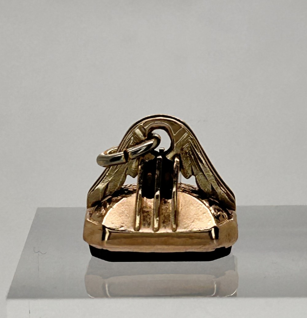 An antique gold watch fob pendant featuring hand-engraved leaf patterns on an arched mount with a top attachment ring. View III