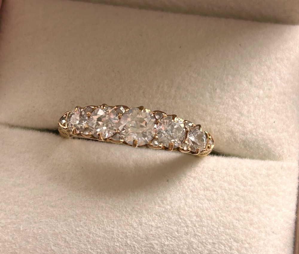 An antique Victorian gold ring featuring five graduated diamonds set into an openwork scroll gallery. View II