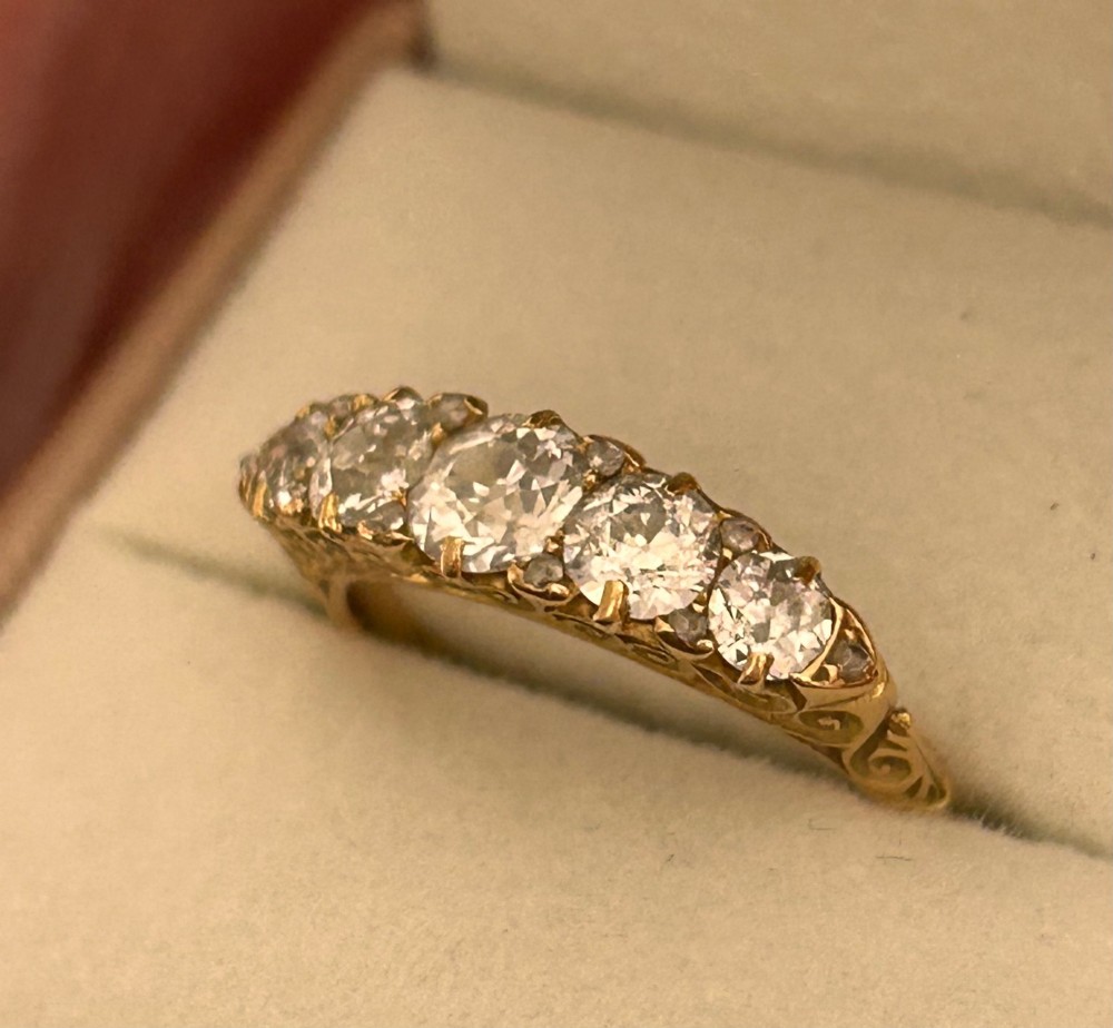 An antique Victorian gold ring featuring five graduated diamonds set into an openwork scroll gallery. View III