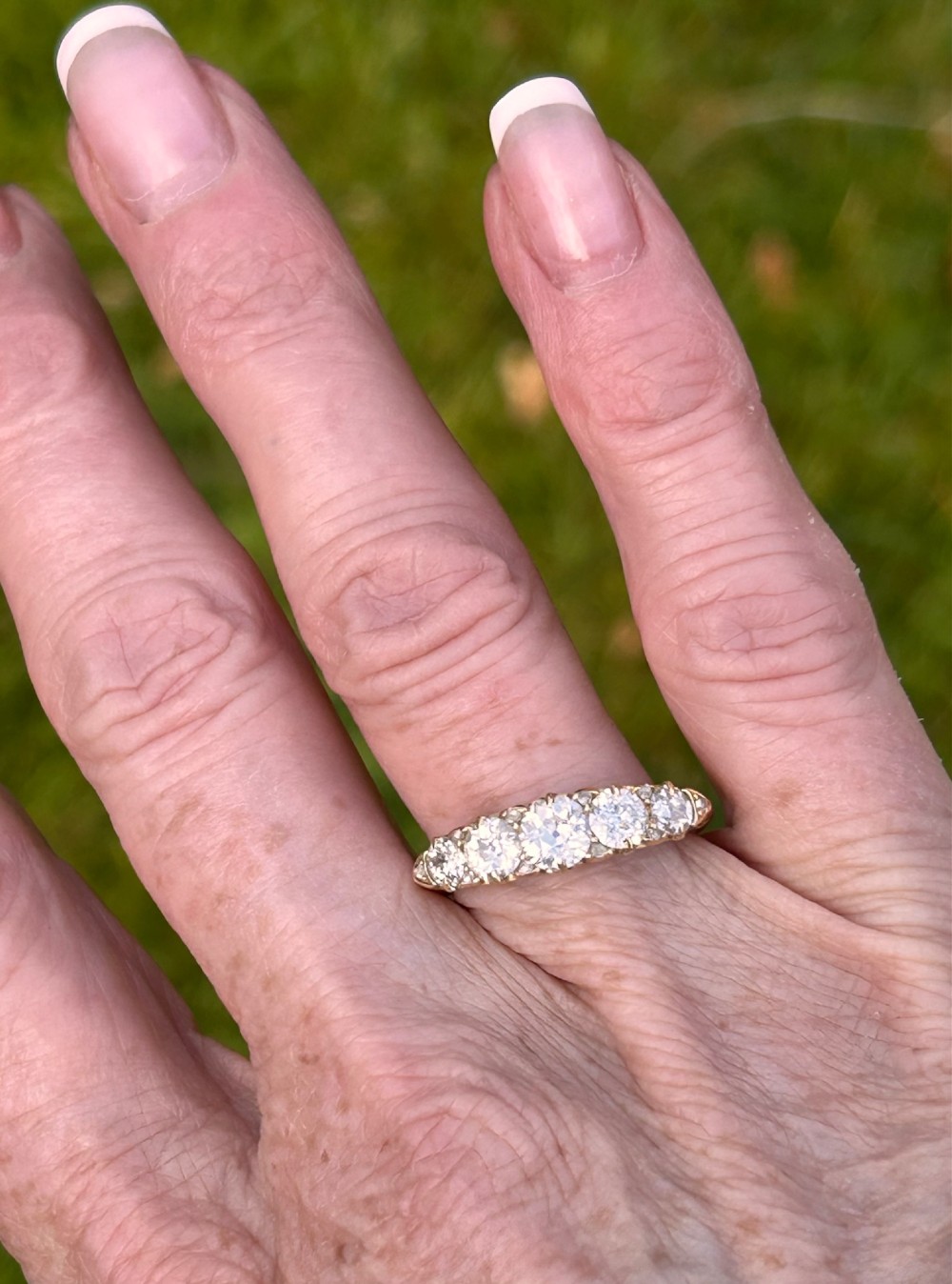 An antique Victorian gold ring featuring five graduated diamonds set into an openwork scroll gallery. View V