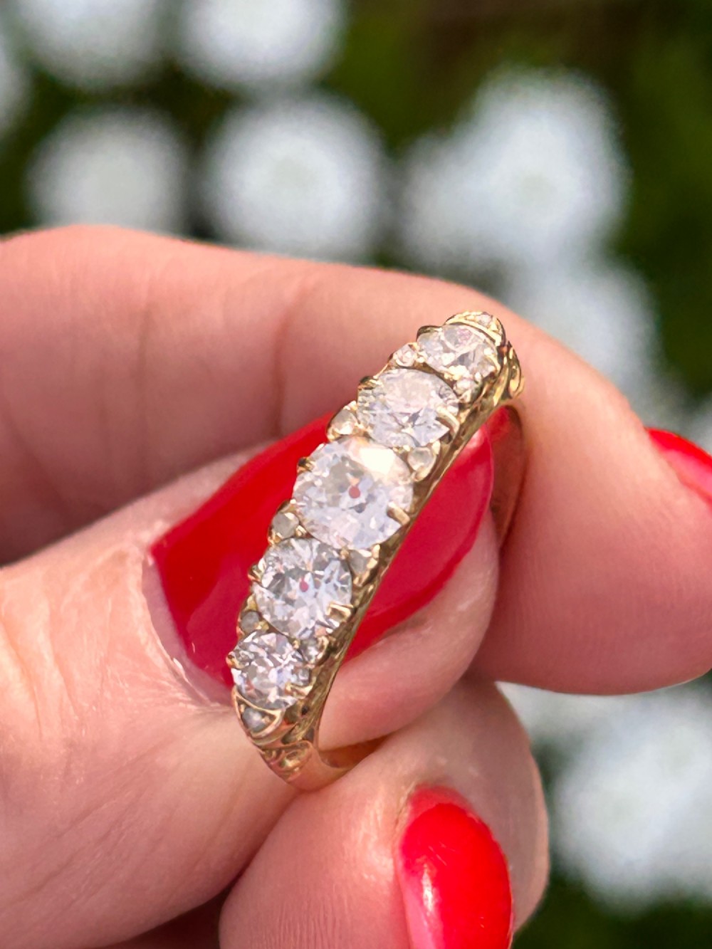 An antique Victorian gold ring featuring five graduated diamonds set into an openwork scroll gallery. View VII