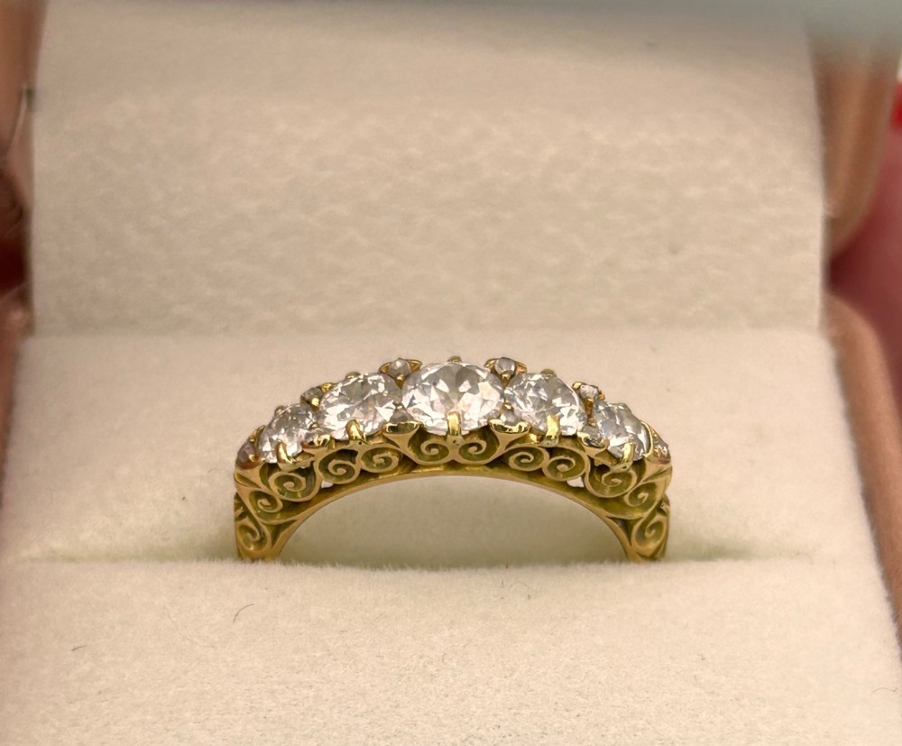 An antique Victorian gold ring featuring five graduated diamonds set into an openwork scroll gallery. View XI