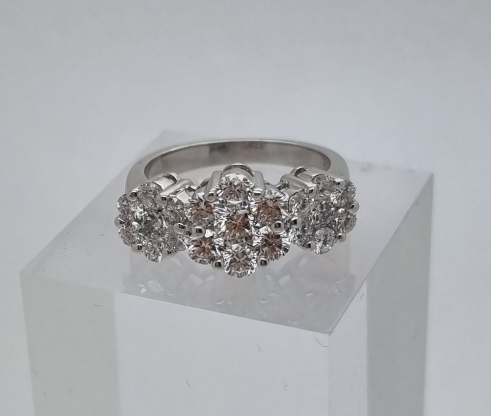 A platinum ring featuring three distinct floral cluster settings mounted with round brilliant diamonds on a smooth band. View II