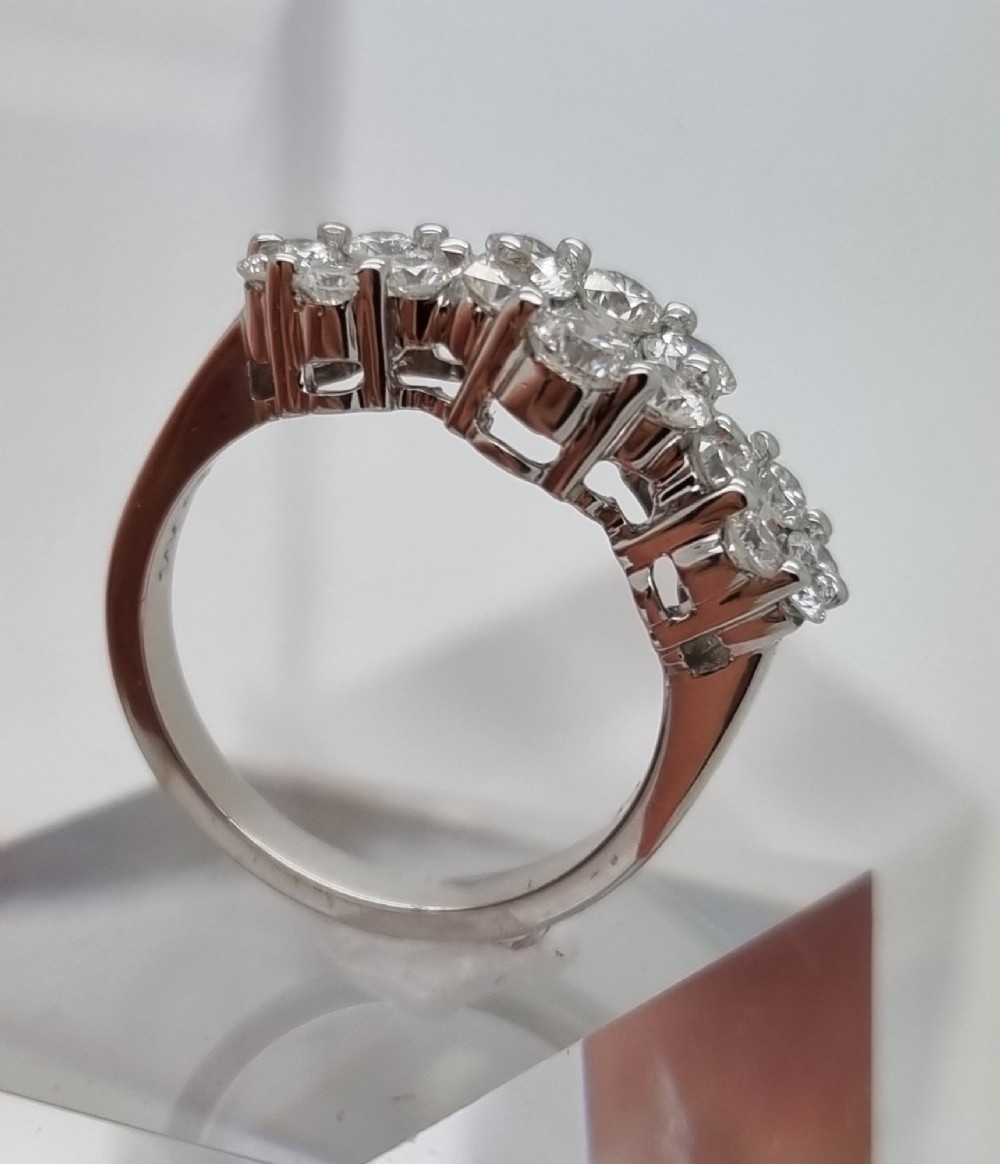 A platinum ring featuring three distinct floral cluster settings mounted with round brilliant diamonds on a smooth band. View III