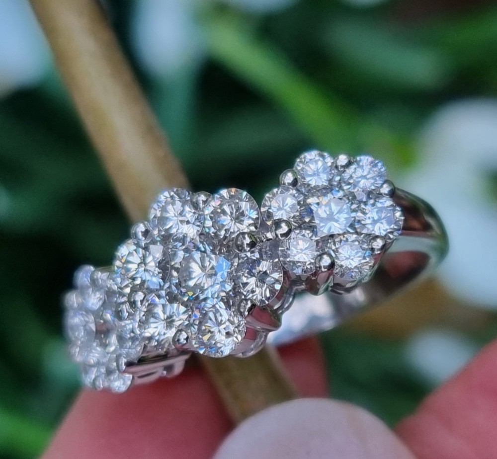 A platinum ring featuring three distinct floral cluster settings mounted with round brilliant diamonds on a smooth band. View IV