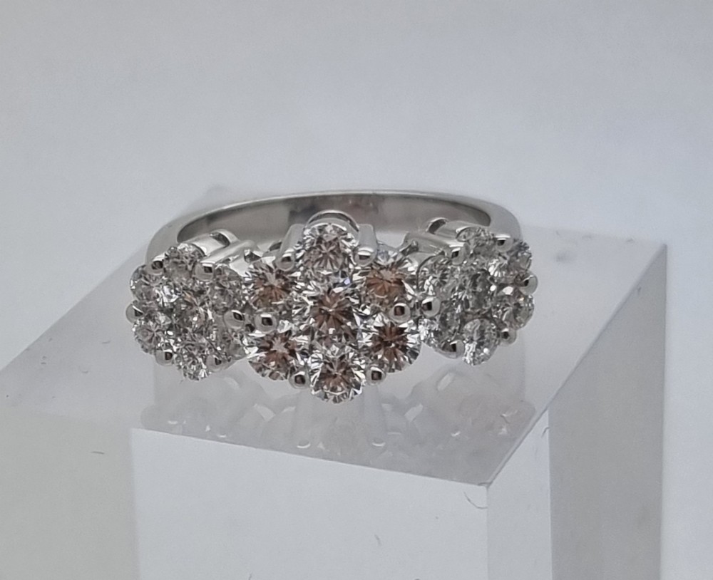 A platinum ring featuring three distinct floral cluster settings mounted with round brilliant diamonds on a smooth band. View VII