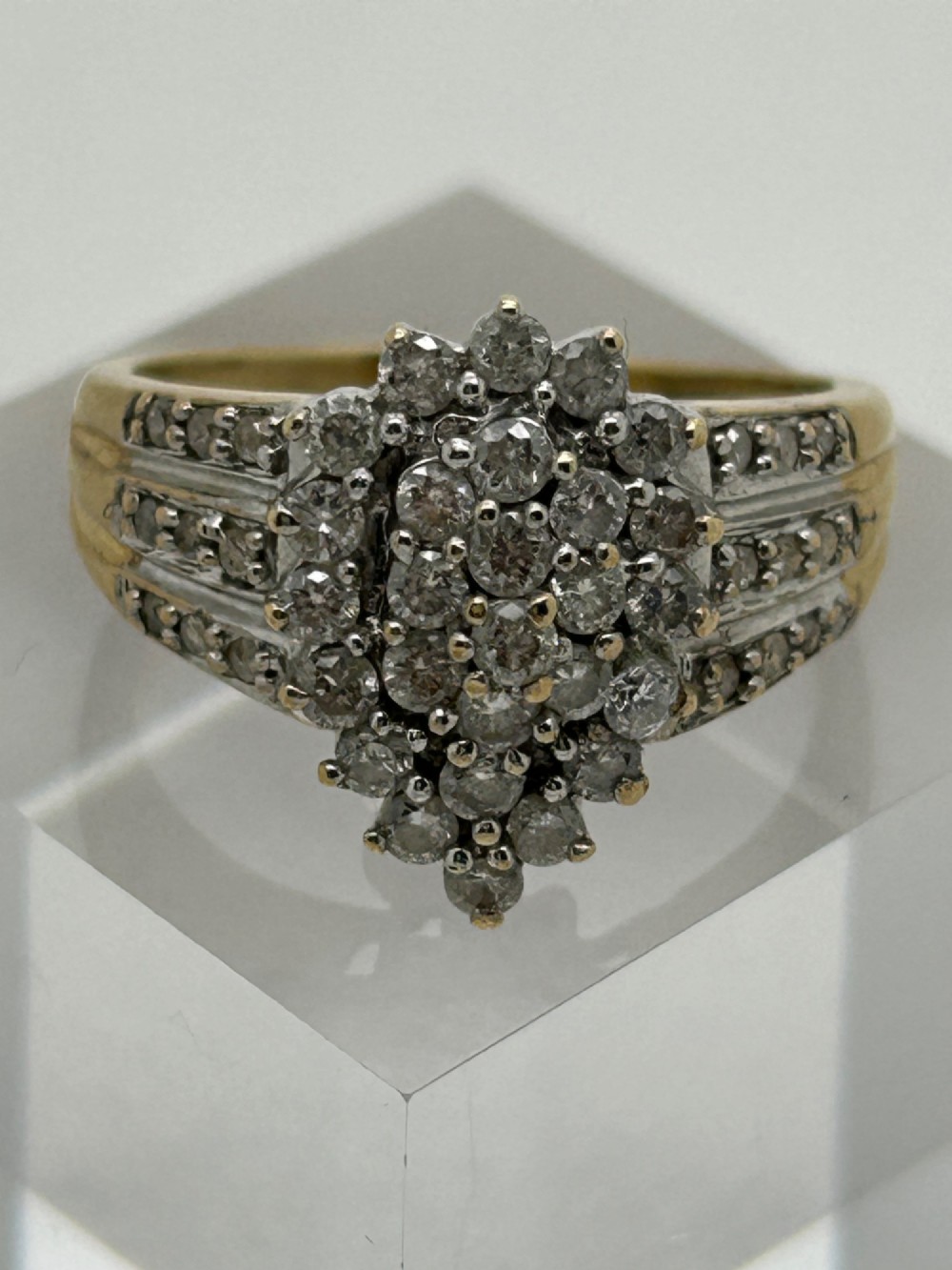 A yellow gold band ring features a central teardrop-shaped cluster of small round diamonds with additional pave diamonds set into the shoulders.