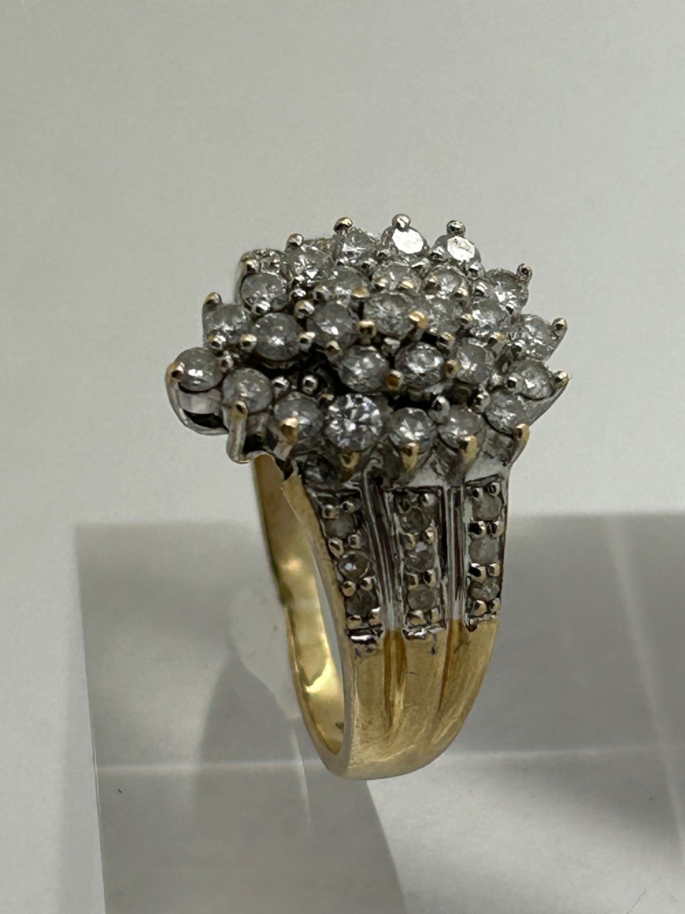 A yellow gold band ring features a central teardrop-shaped cluster of small round diamonds with additional pave diamonds set into the shoulders. View III