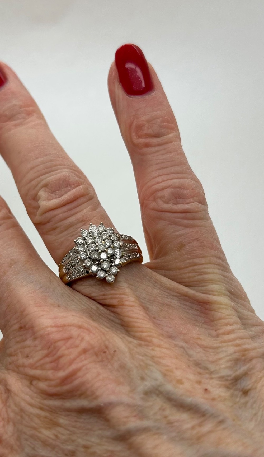 A yellow gold band ring features a central teardrop-shaped cluster of small round diamonds with additional pave diamonds set into the shoulders. View V