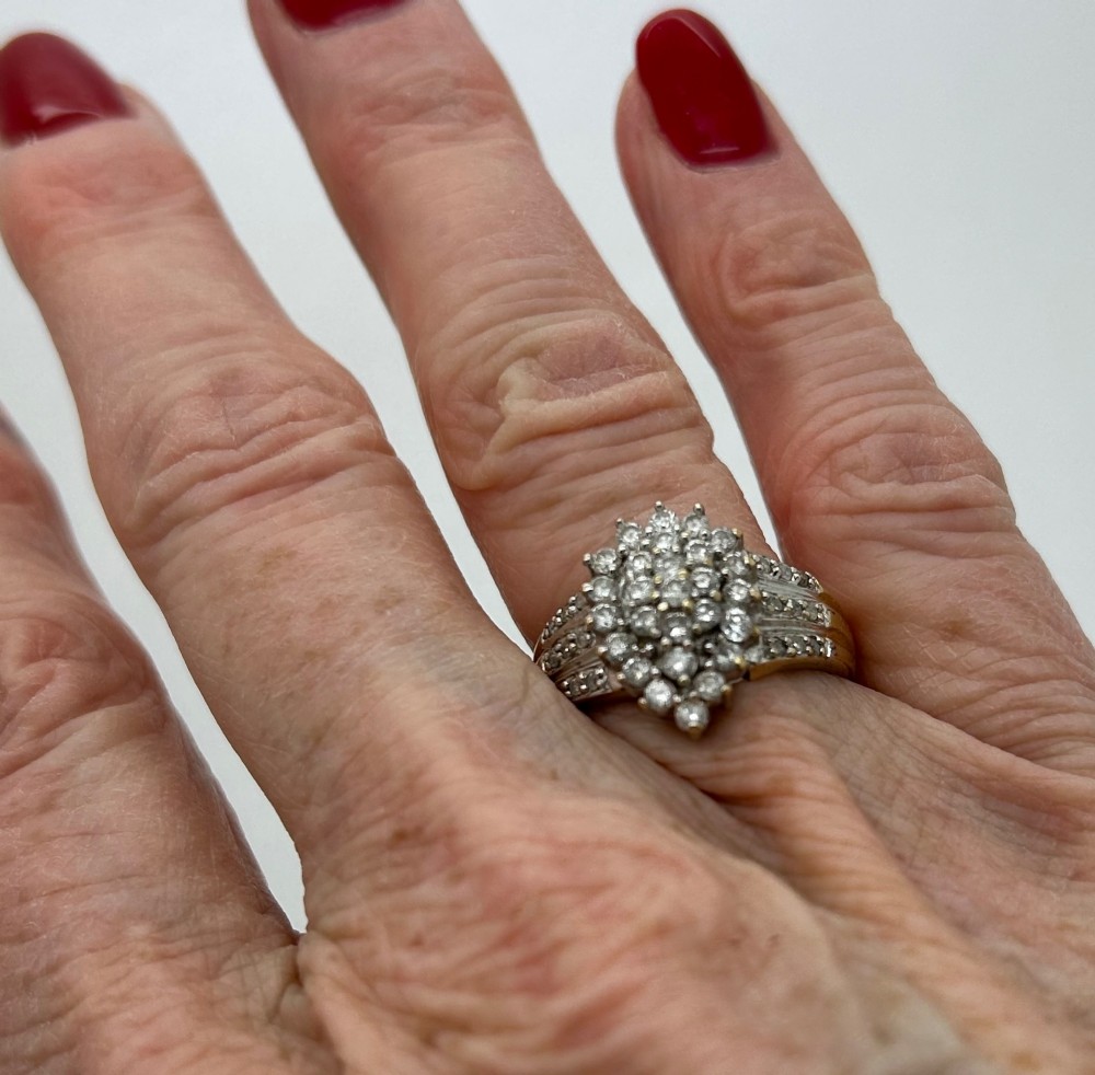 A yellow gold band ring features a central teardrop-shaped cluster of small round diamonds with additional pave diamonds set into the shoulders. View VI