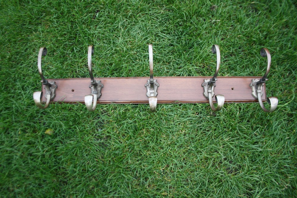 Five Edwardian coat-hooks mounted on walnut