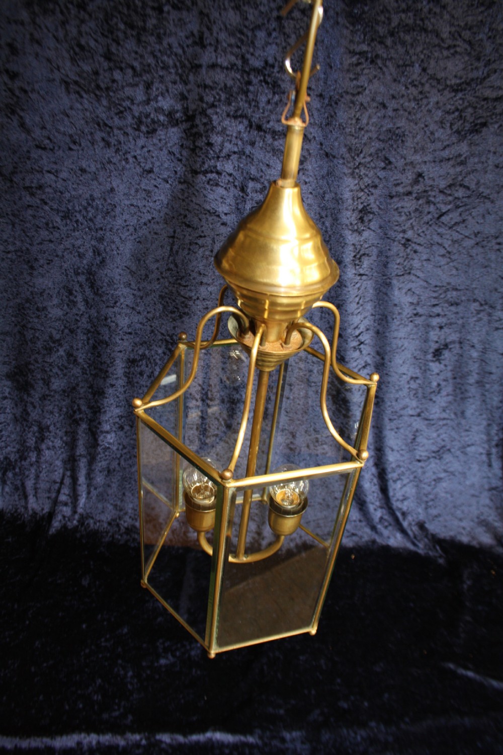 An early twentieth-century hexagonal brass hall lantern featuring six clear glass panels and a central light fixture suspended from a hooked top. View II