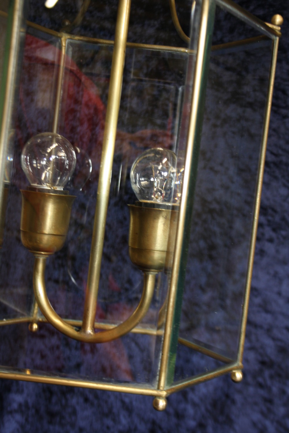 An early twentieth-century hexagonal brass hall lantern featuring six clear glass panels and a central light fixture suspended from a hooked top. View VI