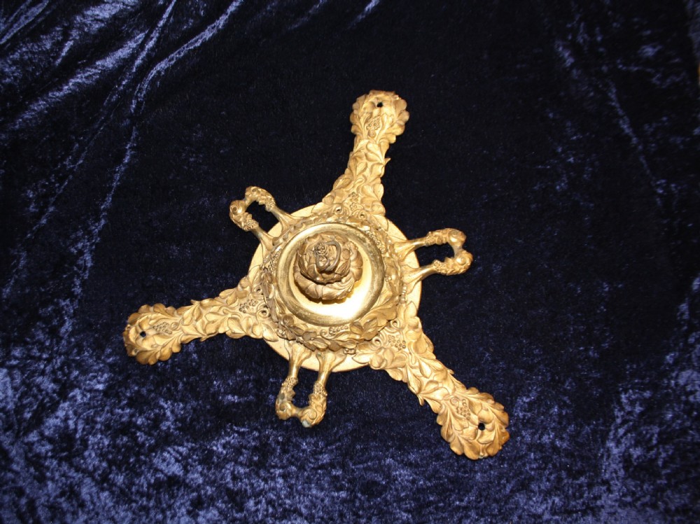 An ornate cast gilt brass ceiling rose featuring three foliate arms, grape and leaf motifs, and a central mounting hook.