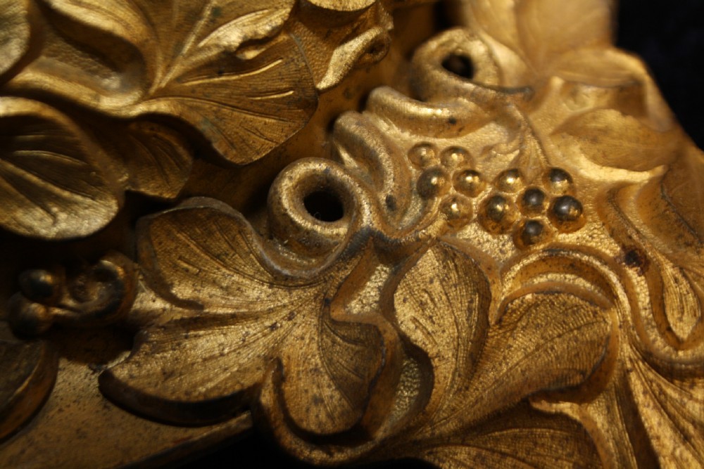An ornate cast gilt brass ceiling rose featuring three foliate arms, grape and leaf motifs, and a central mounting hook. View IX