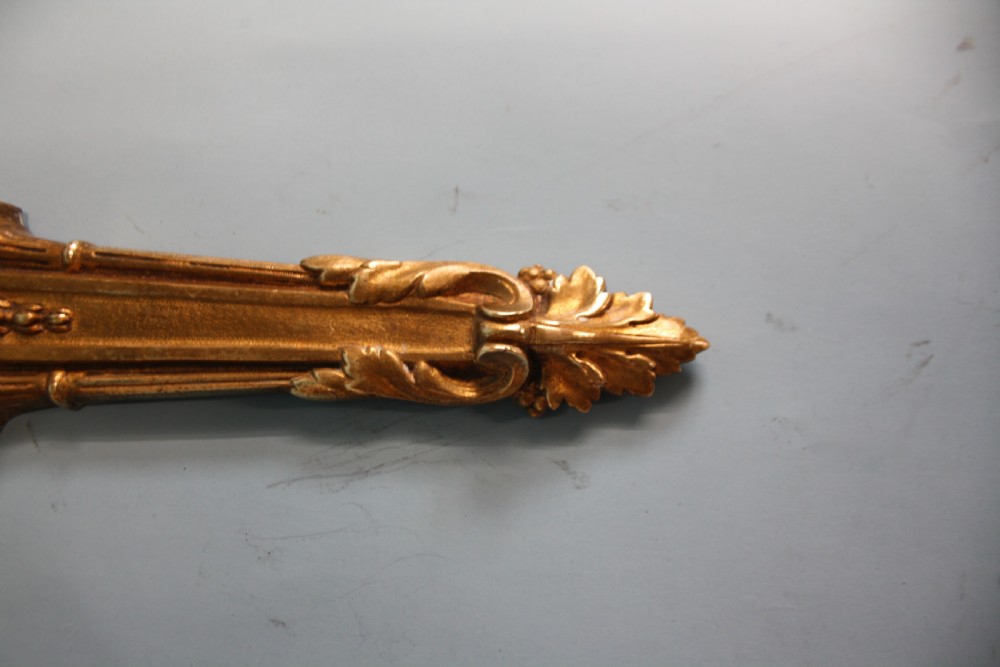 A pair of early 20th-century cast brass twin-arm wall lights featuring a cherub face motif and detailed foliate scrollwork. View IX