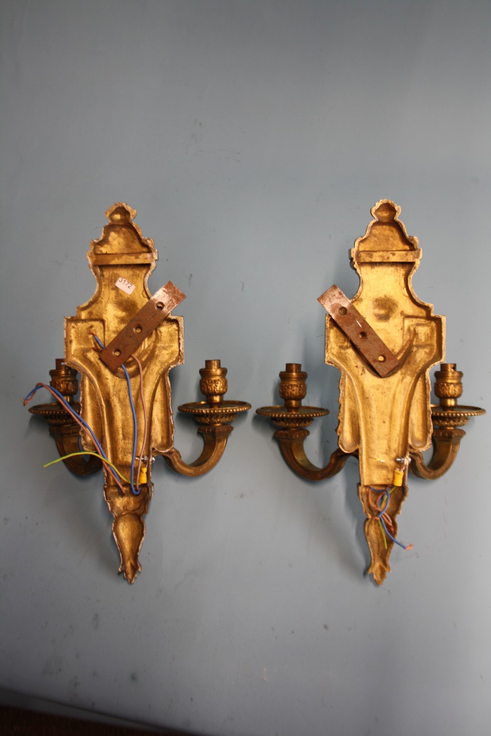 A pair of early 20th-century cast brass twin-arm wall sconces featuring Neoclassical garland and wreath embellishments. View II