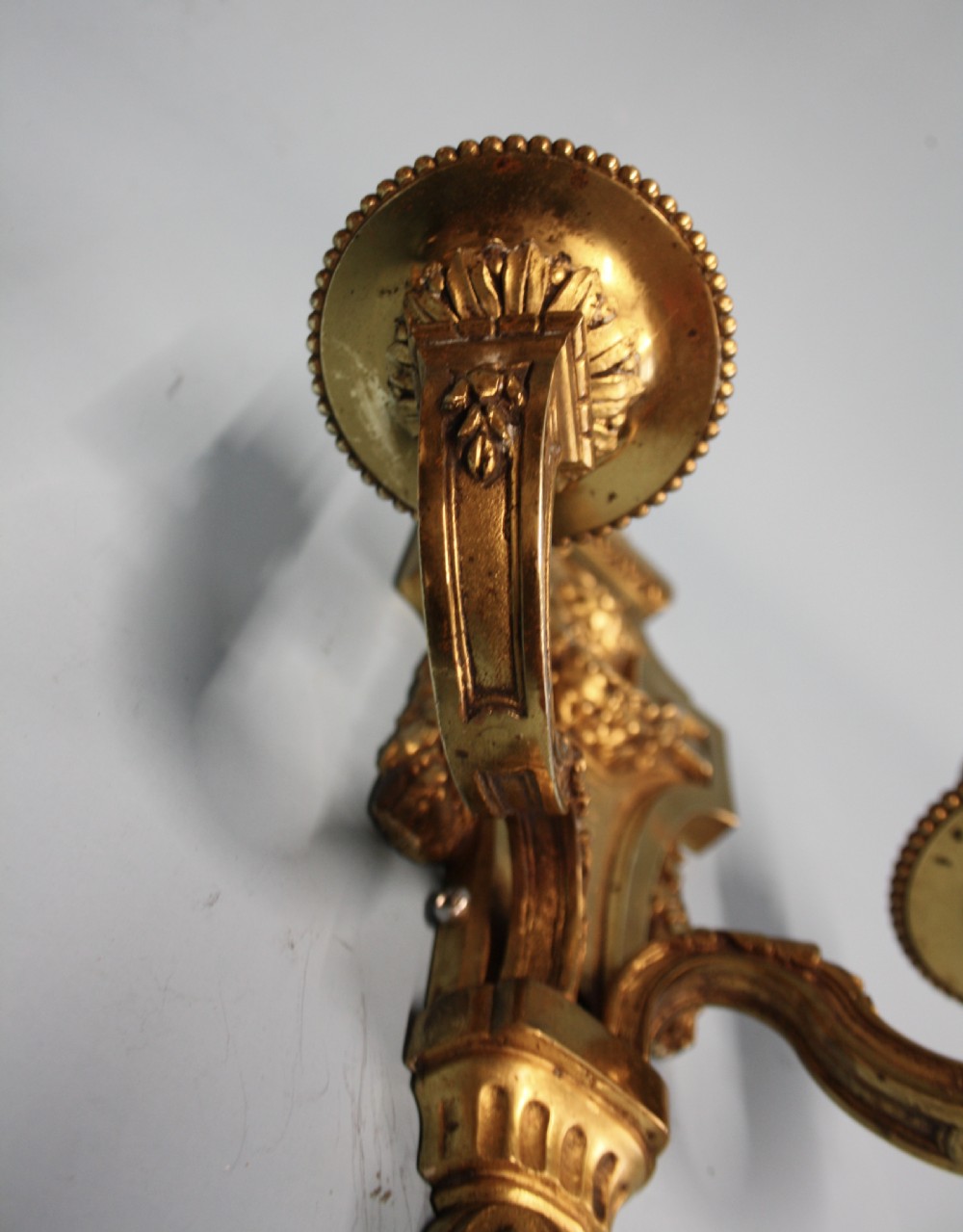 A pair of early 20th-century cast brass twin-arm wall sconces featuring Neoclassical garland and wreath embellishments. View VII