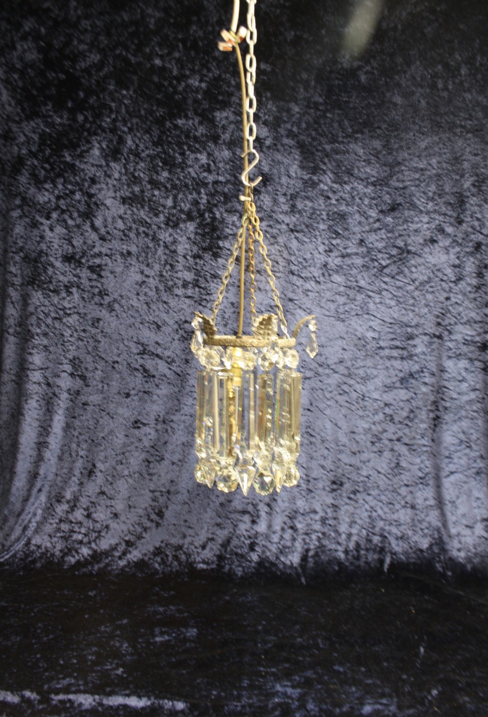 An early 20th century ceiling pendant featuring vertical glass prism lustres suspended from a brass gallery ring and hanging chain.