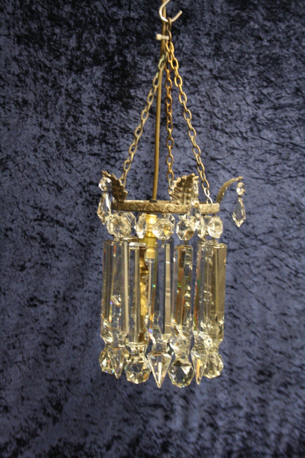 An early 20th century ceiling pendant featuring vertical glass prism lustres suspended from a brass gallery ring and hanging chain. View II