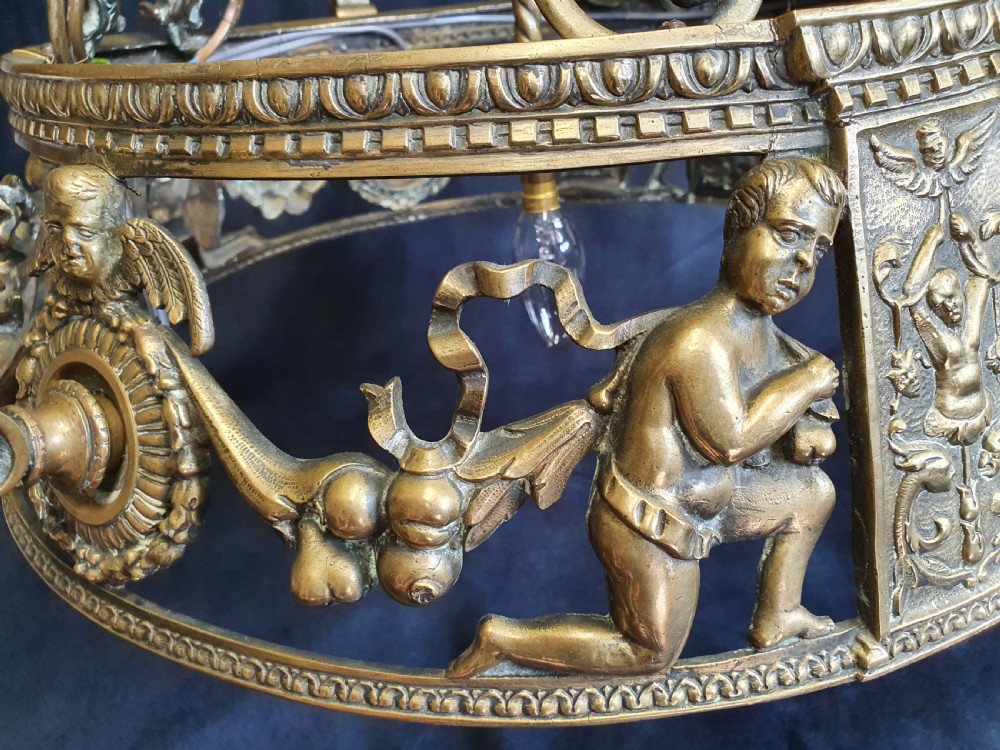 An Edwardian brass four-light chandelier featuring cast cherub figures, decorative swags, and a green fabric shade with hanging fringe. View VII