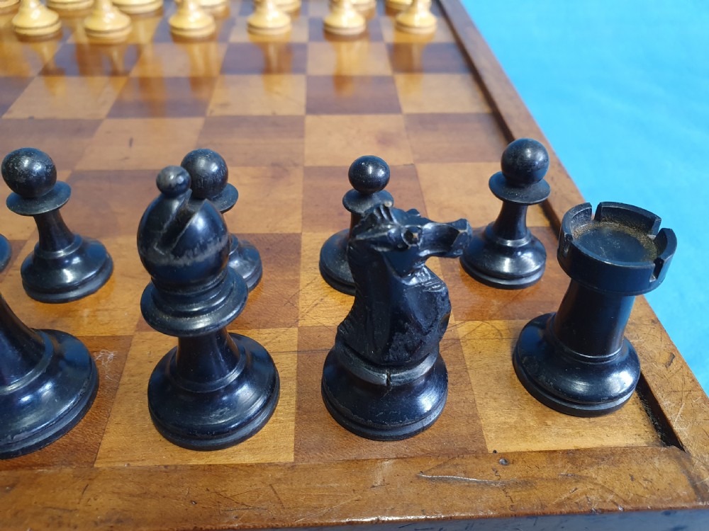 A Victorian wooden folding chess board box displaying full black and natural boxwood Staunton pattern chess pieces. View X