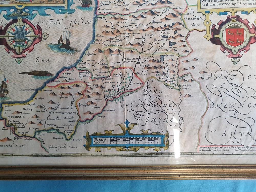 A framed 17th-century hand-coloured map of Cardiganshire featuring cartouches, heraldic coats of arms, and an inset town plan. View III
