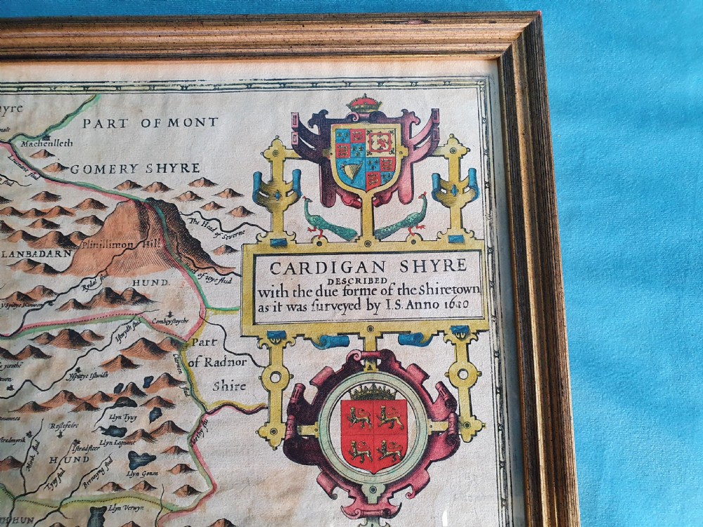 A framed 17th-century hand-coloured map of Cardiganshire featuring cartouches, heraldic coats of arms, and an inset town plan. View V