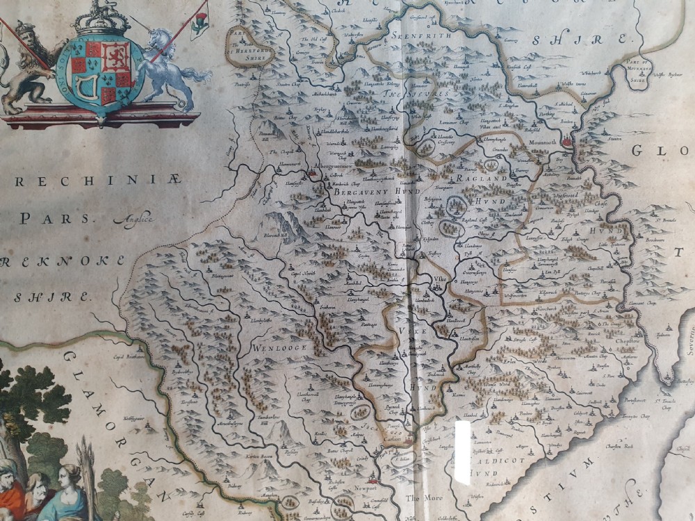 A framed 17th-century hand-coloured map of Monmouthshire featuring coats of arms, figures, a decorative cartouche, and a gilded wood frame. View III